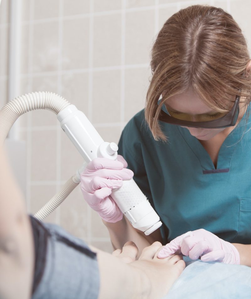 female-cosmetician-doing-foot-therapy-using-laser